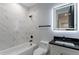 This bathroom has marbled wall tile, black trim, a white tub and toilet, and a vanity with black countertop at 676 S Grand Nw Ave, Atlanta, GA 30318