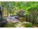 Inviting backyard featuring a stone paver checkerboard patio, a seating wall, and natural rock steps amid a bamboo forest at 265 Tara Trl, Atlanta, GA 30327