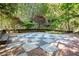 Beautiful backyard with a stone paver checkerboard patio, stone wall, and lush landscaping surrounded by bamboo trees at 265 Tara Trl, Atlanta, GA 30327