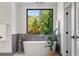 Bathroom featuring a modern tub and a large window with serene views of nature at 265 Tara Trl, Atlanta, GA 30327