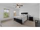 Bedroom featuring a black bedframe, matching nightstand, two windows, and neutral carpeting at 8275 Majors Ridge Way, Cumming, GA 30041