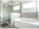 Bright bathroom features a tiled shower, a soaking tub and a large window at 2649 Ogden Trl, Buford, GA 30519