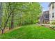 Lush green backyard with mature trees and a portion of home with stairs, mulch flower beds, and green grass at 1315 Woodland Trce, Cumming, GA 30041