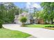 Lovely front exterior with well-manicured lawn, long driveway and professional landscaping on sunny day at 1315 Woodland Trce, Cumming, GA 30041