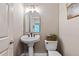 A neutral powder room with a pedestal sink and decorative mirror at 1315 Woodland Trce, Cumming, GA 30041