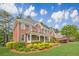 Traditional two-story brick home featuring a well-manicured lawn, mature landscaping, and a covered front porch at 1611 Threepine Pl, Lilburn, GA 30047