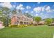 Beautiful brick home with a manicured lawn, mature trees, colorful landscaping, and a welcoming front porch at 1611 Threepine Pl, Lilburn, GA 30047