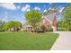 Picturesque brick home featuring a green lawn, mature trees, colorful landscaping, and a side-entry two-car garage at 1611 Threepine Pl, Lilburn, GA 30047