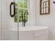 Bathroom with a modern freestanding tub next to a large window with white curtains at 521 Smithstone Se Rd, Marietta, GA 30067