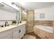 Elegant bathroom featuring double vanity, glass shower, and a luxurious soaking tub with decorative stone tile at 1612 Alder Se Ct, Atlanta, GA 30317