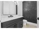 Modern bathroom with a dark vanity and sleek, black faucet, and designer textured accent wall at 407 Thunder Rd, Buford, GA 30518