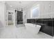 Luxurious bathroom with a freestanding tub, glass shower, and marble-tiled walls for a spa-like experience at 407 Thunder Rd, Buford, GA 30518