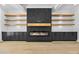 Modern fireplace feature wall with floating shelves and cabinets in a room with hardwood floors at 407 Thunder Rd, Buford, GA 30518