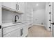 Bright laundry room featuring a built-in sink with white cabinets and shelving at 407 Thunder Rd, Buford, GA 30518
