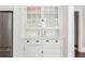 Detailed view of a white cabinet with glass doors, decorative items, and storage drawers at 1012 Bellevue Ne Dr, Atlanta, GA 30306