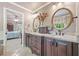 Well-lit bathroom with double sinks, granite countertops, dark wood cabinets and open to the main bedroom at 2885 Arborwoods Dr, Alpharetta, GA 30022
