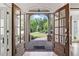 Grand entryway with double glass doors, showcasing a view of the lush front yard and manicured landscaping at 330 Plantation Way, Roswell, GA 30075