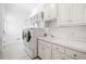 Well-lit laundry room with washer, dryer, white cabinets and counter space at 330 Plantation Way, Roswell, GA 30075