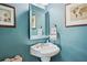 Stylish powder room with blue walls, decorative mirror, and pedestal sink at 330 Plantation Way, Roswell, GA 30075