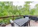 Outdoor deck with a dining table set overlooking a lush, green, wooded view at 3097 Trinity Grove Dr, Dacula, GA 30019