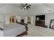 This main bedroom features an elegant tray ceiling, a ceiling fan, and a large dresser with a television on top at 3097 Trinity Grove Dr, Dacula, GA 30019