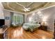 Spacious main bedroom featuring hardwood floors, tray ceilings, and a cozy sitting area by a large window at 1144 Bellewood Sq, Dunwoody, GA 30338