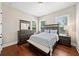 Cozy bedroom with hardwood floors, a matching furniture set, and two bright windows with pleasant views at 6090 Pennant Ln, Suwanee, GA 30024