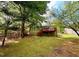 A quaint, grassy backyard with a cozy deck and a backdrop of lush, mature trees offering shade and privacy at 921 Hemingway Rd, Stone Mountain, GA 30088