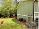 Side yard with green grass and shrubbery, an AC unit, and view of green home exterior with white trim at 921 Hemingway Rd, Stone Mountain, GA 30088