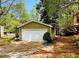 Detached two-car garage with a white door, complemented by the adjacent home's exterior and lush greenery at 921 Hemingway Rd, Stone Mountain, GA 30088