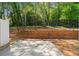 Rear patio with wood retaining wall and black fence and treed landscape at 1067 Brittania Rd, Stone Mountain, GA 30083