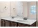 Double sink bathroom vanity with dark cabinets, a large mirror, and natural light at 1067 Brittania Rd, Stone Mountain, GA 30083