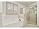 Bright bathroom featuring a soaking tub beneath a shuttered window and a glass-enclosed shower at 28 Summer Nw Pl, Cartersville, GA 30121