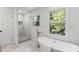 Bathroom featuring freestanding tub with leafy backyard views and a seamless glass shower at 1047 Winding Branch Ct, Atlanta, GA 30338