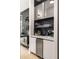 Stylish bar area featuring glass shelves, dark backsplash, stainless steel appliances, and white cabinetry at 2469 River Oak Dr, Decatur, GA 30033