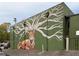 The Grove mural featuring a stag and tree branch antlers painted on the side of the green building at 2469 River Oak Dr, Decatur, GA 30033