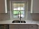Kitchen sink with stainless steel faucet, white cabinets, and countertop with a view of the backyard at 713 Parkside Dr, Woodstock, GA 30188