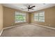 A simple bedroom with beige carpet, neutral walls, ceiling fan, and two bright windows at 1008 Lena Nw St, Atlanta, GA 30314