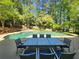 Inviting outdoor pool surrounded by mature trees and a patio area with outdoor seating at 7635 Blandford Pl, Atlanta, GA 30350