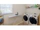 Bright laundry room with modern washer and dryer, ironing board and storage shelves at 2975 Oak Hampton Way, Duluth, GA 30096