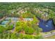 Aerial view showcasing community amenities: tennis courts, a pool, and a serene lake, all surrounded by lush trees at 12340 Preserve Ln, Alpharetta, GA 30005