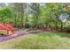Spacious backyard featuring lush greenery, a wooden deck with stairs, and a decorative mulch path at 12340 Preserve Ln, Alpharetta, GA 30005
