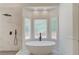 Modern bathroom with a standalone tub, rainfall shower, and large window for natural light at 12340 Preserve Ln, Alpharetta, GA 30005
