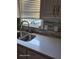 Close-up of a kitchen sink with quartz countertops and a tiled backsplash, enhanced by natural light at 1424 Belmont Rd, Villa Rica, GA 30180