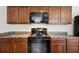 Close-up showcasing the kitchen's electric stove and microwave, paired with wood cabinets at 6904 Estepona St, Atlanta, GA 30349