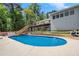 Large in-ground pool with ladder entry, surrounded by a deck and lush landscaping, offering a private outdoor retreat at 135 Longview Rd, Fayetteville, GA 30214