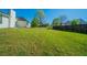 Large grassy backyard with ample space, featuring a wooden fence, mature trees, and views of neighboring homes at 1401 Kala Dr, Lithonia, GA 30058