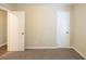 A neutral carpeted bedroom with neutral paint and trim and two white doors at 7268 Westwood Ln, Douglasville, GA 30134