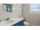 This bathroom features a blue vanity, white sink, round mirror, and a shower/tub combination at 238 Dorothy Ln, Lawrenceville, GA 30046