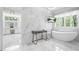Bright bathroom showcasing marble tile, a soaking tub, vanity, and a window overlooking the outdoor greenery at 315 Mossy Pointe, Duluth, GA 30097
